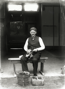 95137 Portret van een oude werknemer in de stal van het huis Kersbergen (?) te Zeist, bezig met het reinigen van een ...